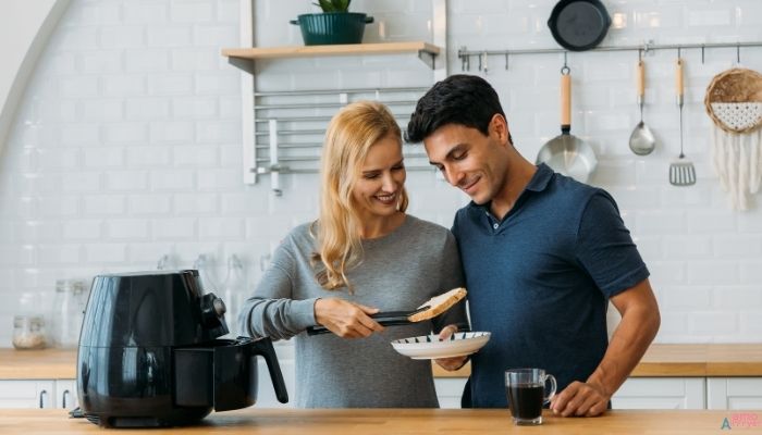 Uma imagem bonita e atraente de uma Airfryer em uma cozinha moderna, com alguns pratos preparados ao redor (como batatas fritas, frango empanado e vegetais)