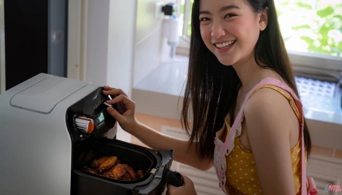 Uma imagem de uma pessoa usando a air fryer de forma casual e satisfatória, com uma expressão de alegria ao ver a comida pronta.